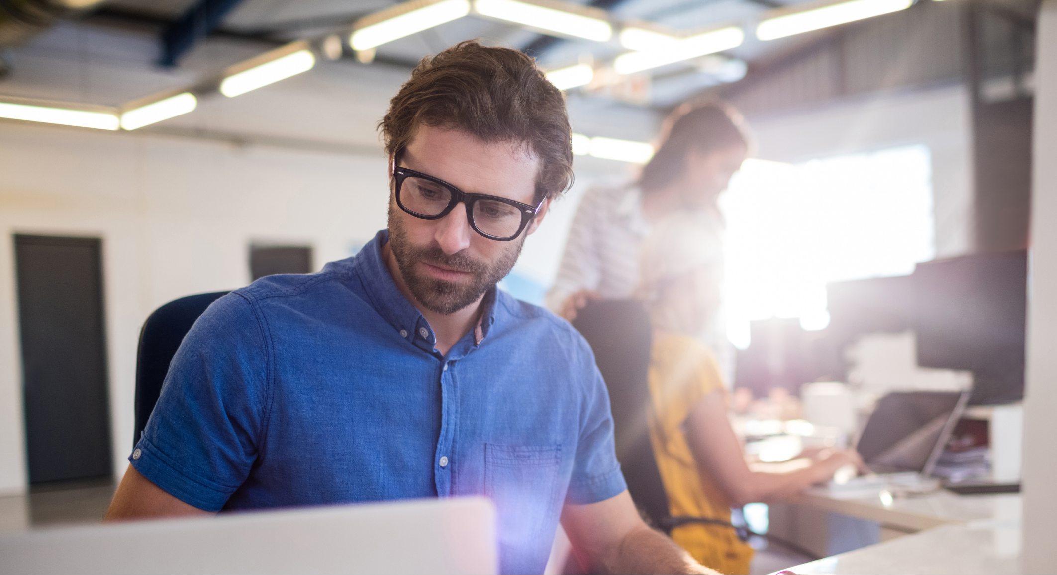 man in a blue shirt looking at intelligent automation on his computer